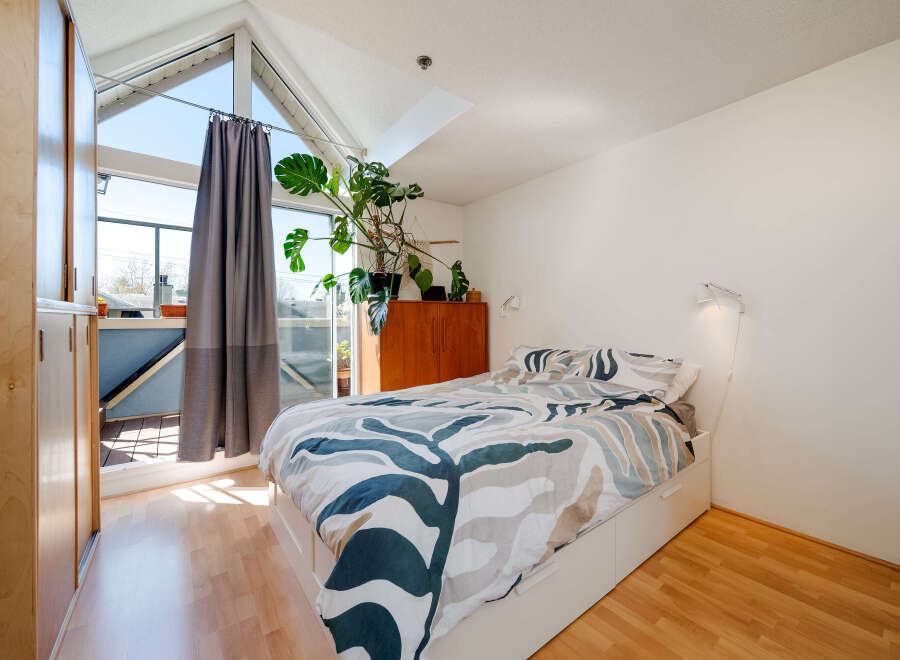 This bright and airy bedroom features a modern design with a large window that floods the space with natural light.