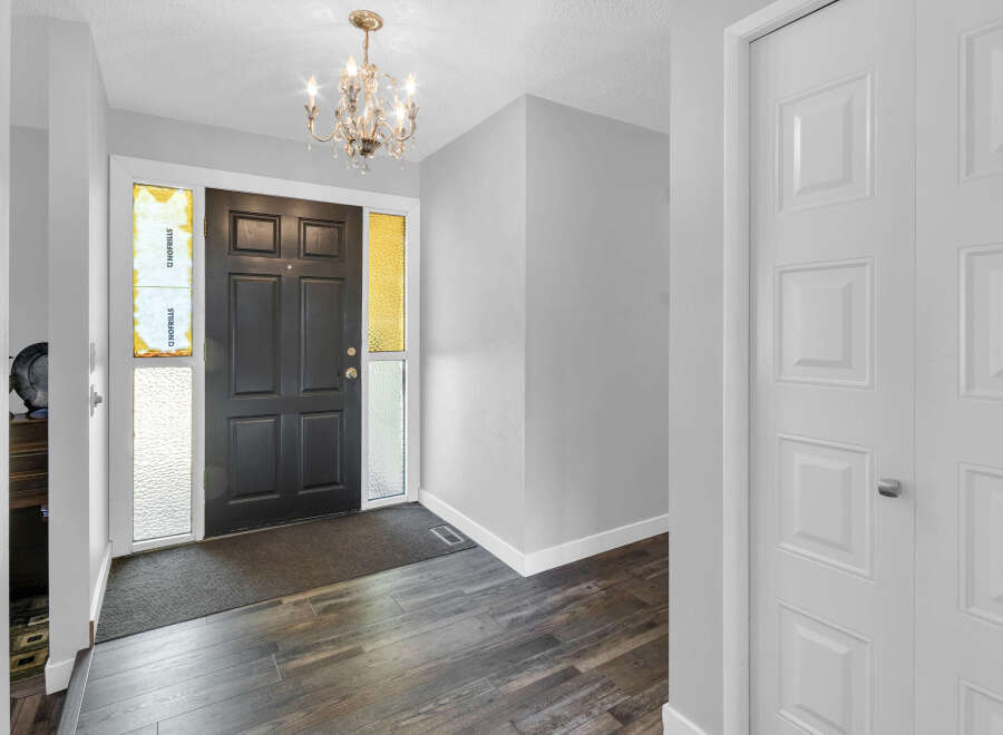 Step into this inviting entryway, featuring a stylish black front door and elegant chandelier.