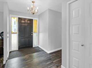 Step into this inviting entryway, featuring a stylish black front door and elegant chandelier.