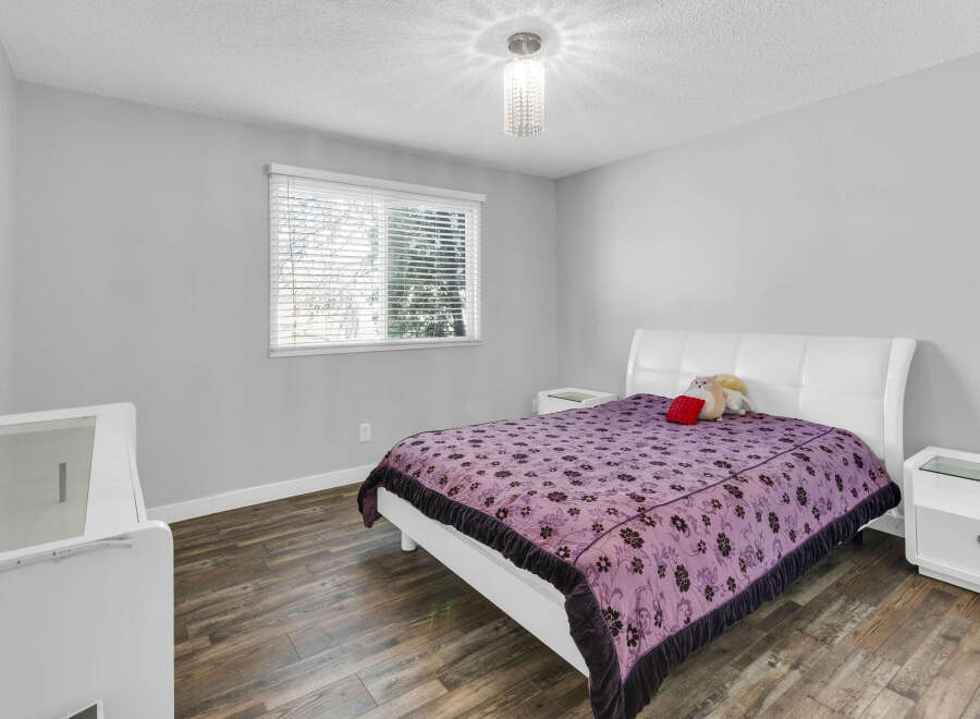 This bedroom offers a serene retreat with its soft gray walls and a cozy queen-sized bed.