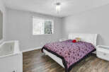 This bedroom offers a serene retreat with its soft gray walls and a cozy queen-sized bed.