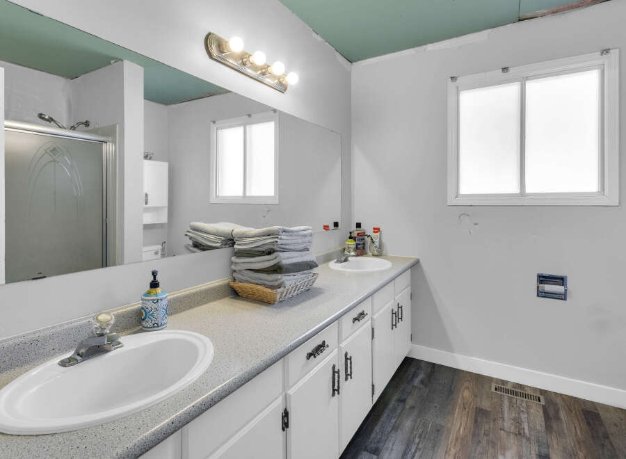 This bathroom features a bright and airy design with a large mirror and ample counter space.