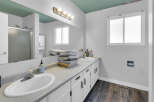 This bathroom features a bright and airy design with a large mirror and ample counter space.