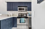This kitchen boasts modern navy blue cabinetry, offering ample storage and a stylish aesthetic.