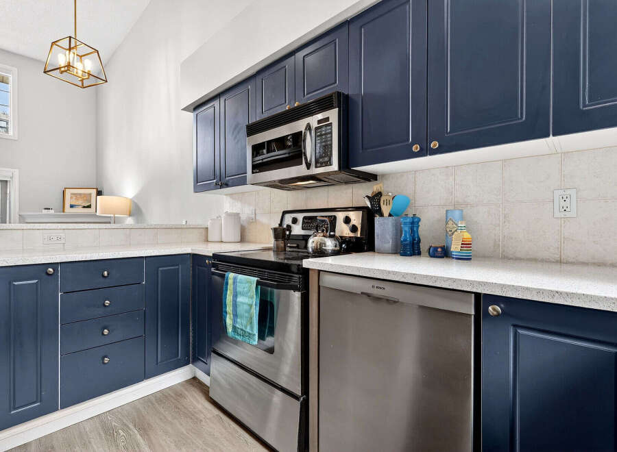 This stunning kitchen boasts modern navy cabinets, offering ample storage and a sleek aesthetic.