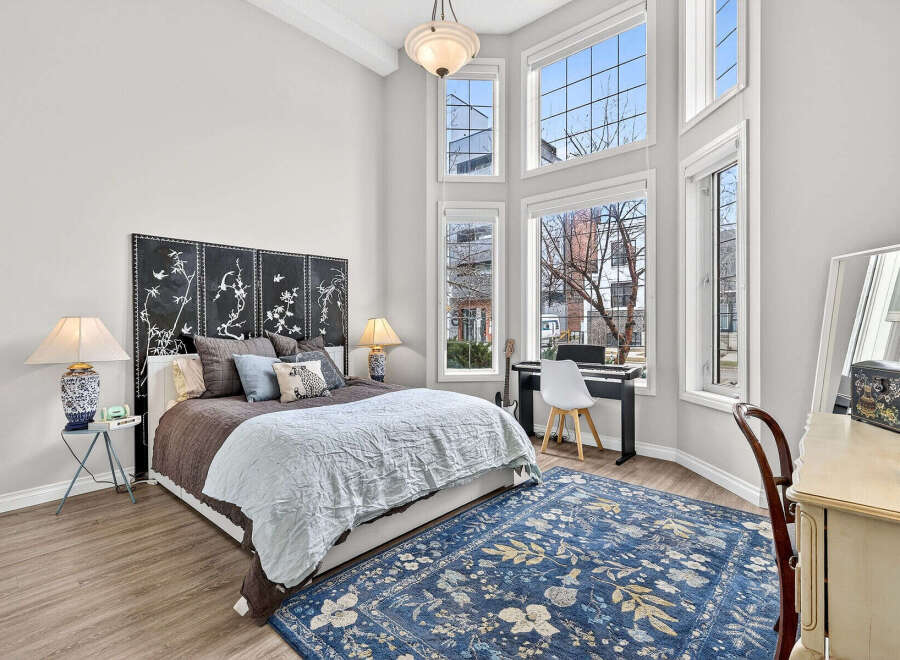 This stunning bedroom boasts a unique design with soaring ceilings and an abundance of natural light streaming through the large windows.