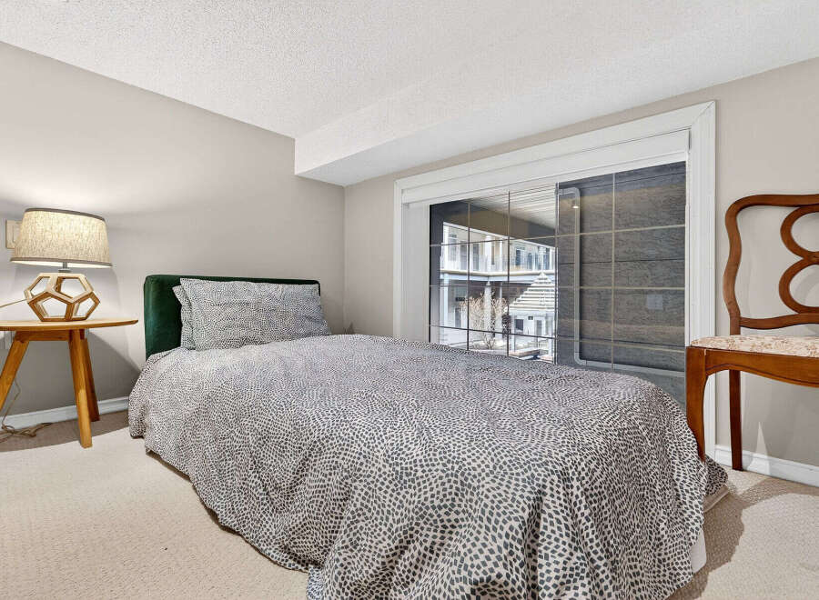 This cozy bedroom features a comfortable bed with a stylish patterned duvet and a plush green headboard.