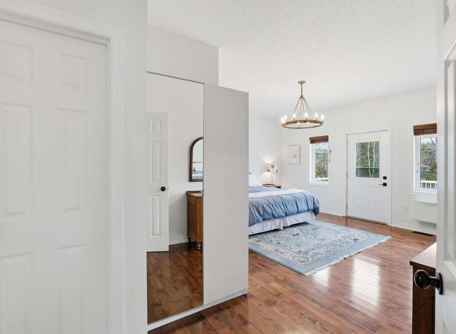 Step into this bright and airy bedroom, featuring beautiful hardwood floors and a stylish chandelier.
