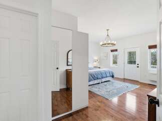 Step into this bright and airy bedroom, featuring beautiful hardwood floors and a stylish chandelier.