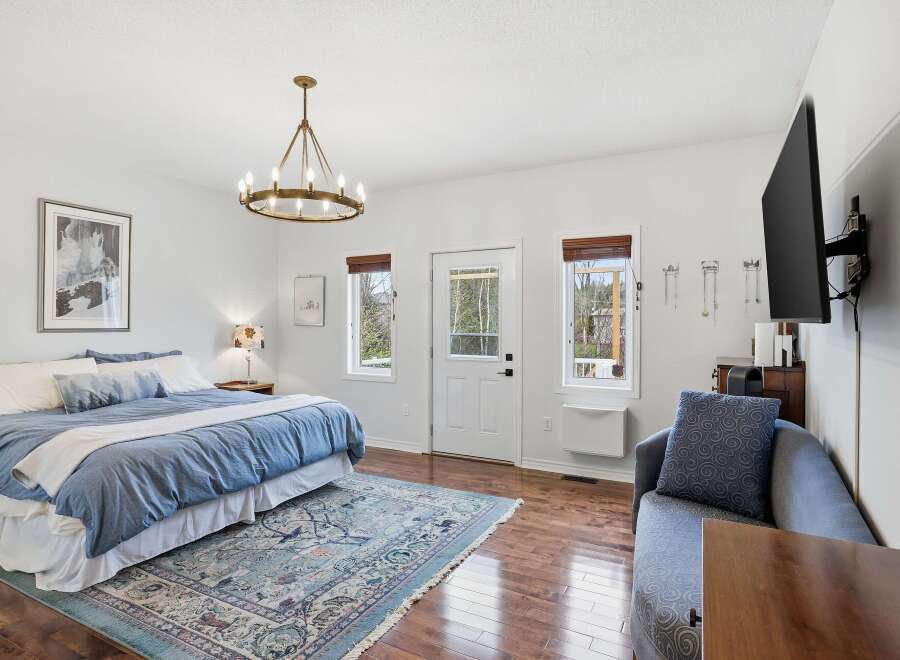Step into this inviting bedroom, featuring a serene ambiance with its soft blue bedding and a touch of elegance with a stylish chandelier.