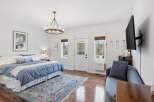 Step into this inviting bedroom, featuring a serene ambiance with its soft blue bedding and a touch of elegance with a stylish chandelier.