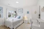 This charming bedroom offers a serene retreat with its elegant white decor and ample natural light.