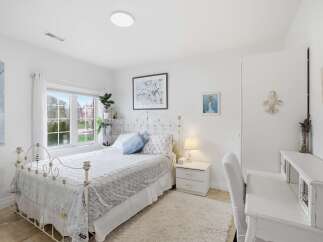 This charming bedroom offers a serene retreat with its elegant white decor and ample natural light.
