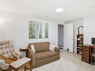 This inviting living space features a cozy sofa, a comfortable armchair, and a stylish artwork, creating a warm and welcoming atmosphere.