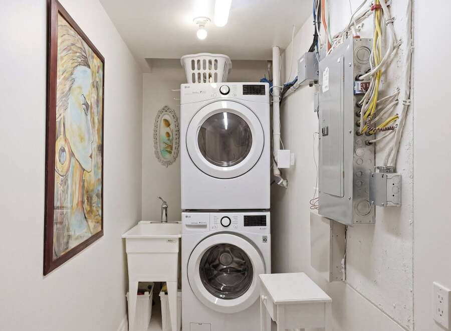 This laundry room features a modern stacked washer and dryer, maximizing space efficiency.