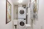 This laundry room features a modern stacked washer and dryer, maximizing space efficiency.