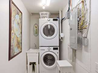 This laundry room features a modern stacked washer and dryer, maximizing space efficiency.