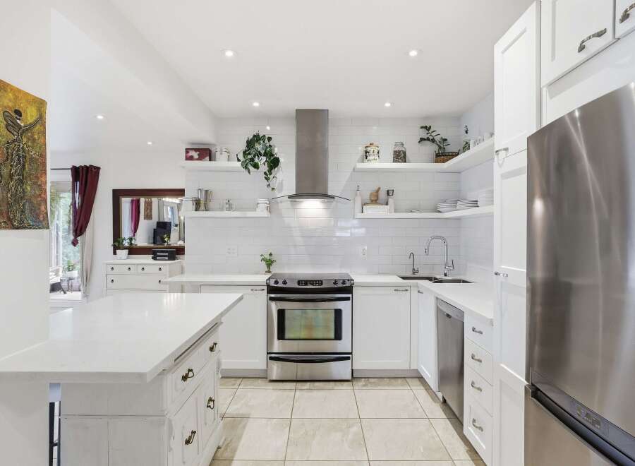 This stunning kitchen boasts a modern design with sleek white cabinetry and countertops, creating a bright and airy atmosphere.