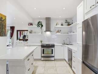 This stunning kitchen boasts a modern design with sleek white cabinetry and countertops, creating a bright and airy atmosphere.