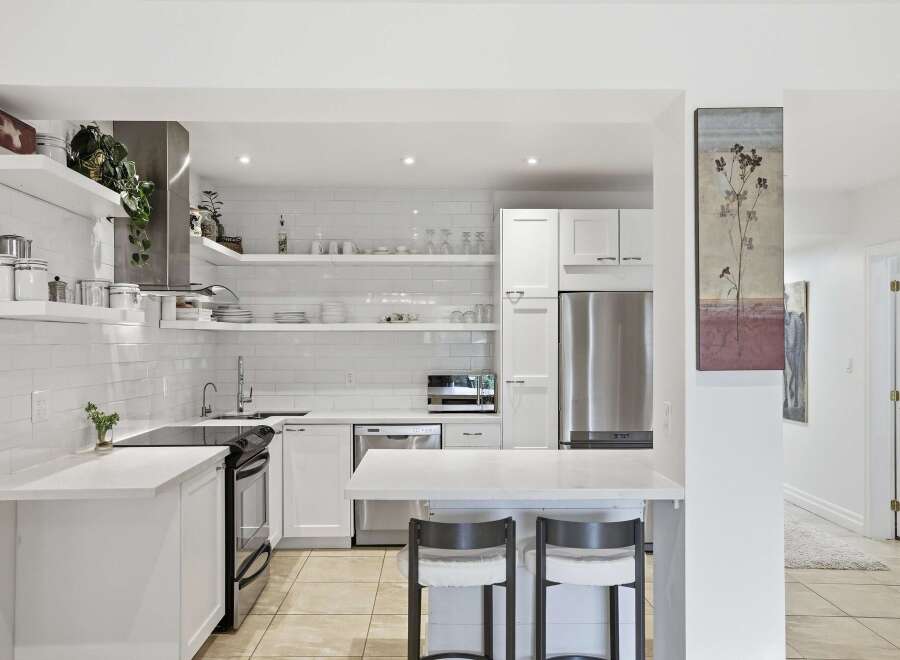 This stunning kitchen boasts a modern design with sleek white cabinetry and countertops, creating a bright and airy atmosphere.