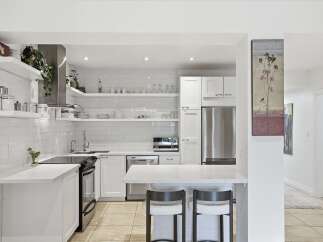 This stunning kitchen boasts a modern design with sleek white cabinetry and countertops, creating a bright and airy atmosphere.