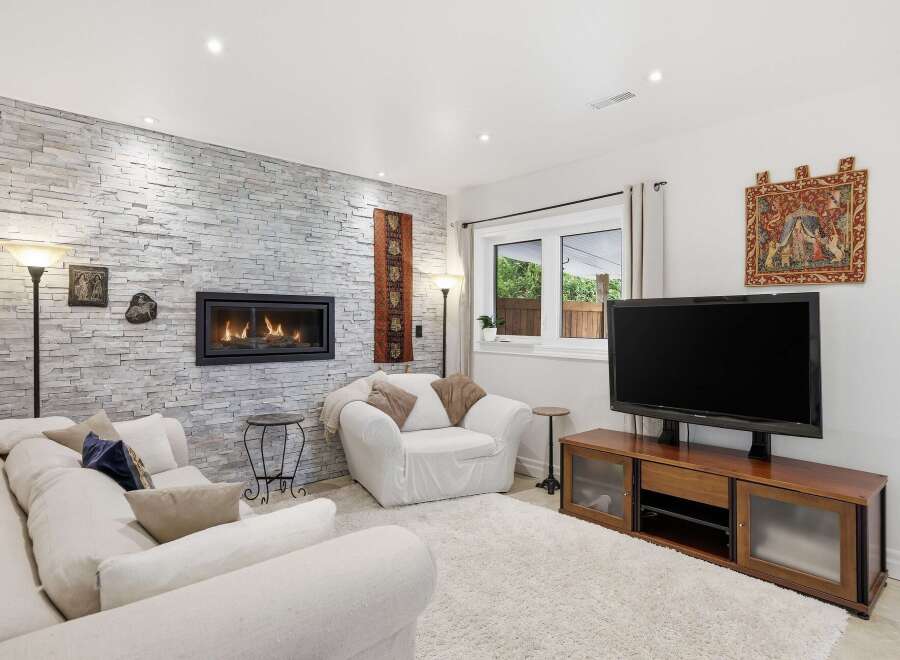 This stunning living room features a cozy fireplace set against a beautiful stone wall, creating a warm and inviting atmosphere.