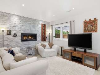 This stunning living room features a cozy fireplace set against a beautiful stone wall, creating a warm and inviting atmosphere.