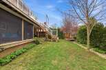 Enjoy outdoor living in this beautiful backyard! This property features a spacious deck with stairs leading down to a lush green lawn.