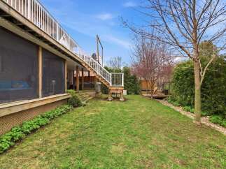 Enjoy outdoor living in this beautiful backyard! This property features a spacious deck with stairs leading down to a lush green lawn.