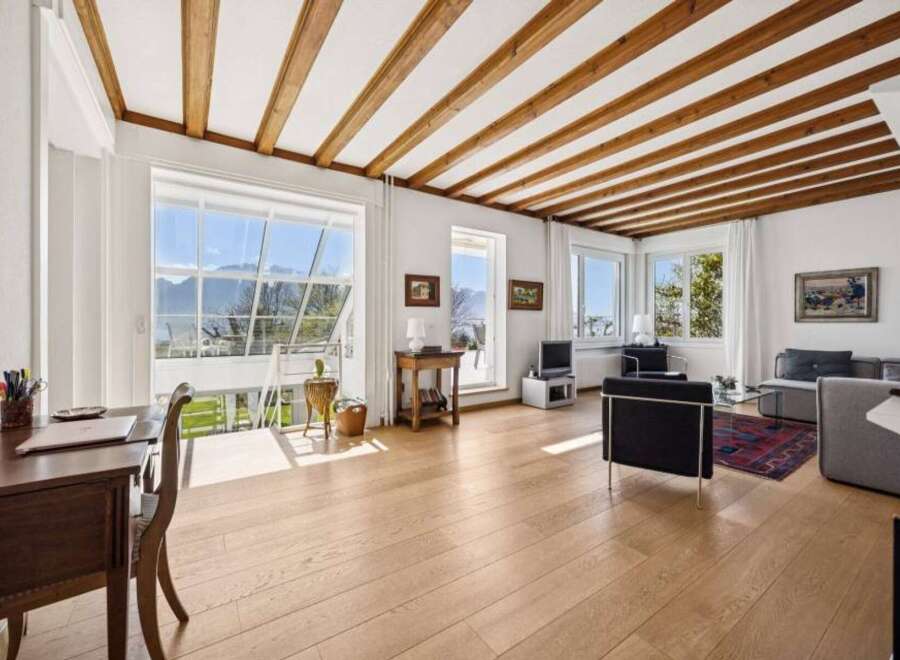 Experience breathtaking mountain views from this stunning living space, featuring a vaulted ceiling with exposed wooden beams and expansive windows that flood the room with natural light.