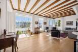 Experience breathtaking mountain views from this stunning living space, featuring a vaulted ceiling with exposed wooden beams and expansive windows that flood the room with natural light.