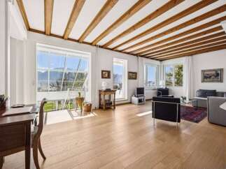 Experience breathtaking mountain views from this stunning living space, featuring a vaulted ceiling with exposed wooden beams and expansive windows that flood the room with natural light.