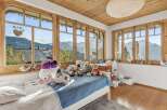 Experience the charm of this cozy bedroom, boasting stunning mountain views framed by elegant wooden windows.