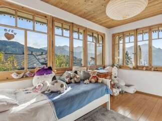 Experience the charm of this cozy bedroom, boasting stunning mountain views framed by elegant wooden windows.