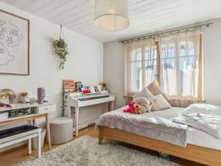 This charming bedroom features a cozy bed, a stylish white piano, and a functional vanity area.