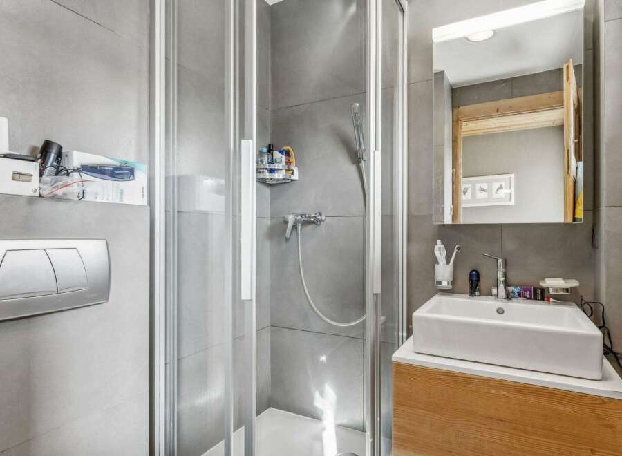 This modern bathroom features a sleek glass shower enclosure, perfect for a refreshing start to your day.