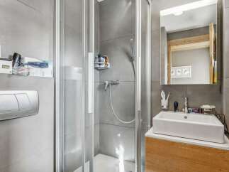 This modern bathroom features a sleek glass shower enclosure, perfect for a refreshing start to your day.