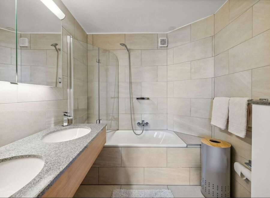This modern bathroom features a sleek design with a double sink vanity and a luxurious soaking tub.