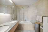 This modern bathroom features a sleek design with a double sink vanity and a luxurious soaking tub.