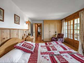 Experience the charm of this cozy bedroom, featuring a rustic wooden bed frame and a beautifully patterned quilt.