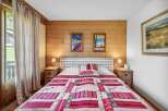 Cozy bedroom with a rustic charm, featuring a wooden wall and a comfortable bed adorned with a vibrant quilt.