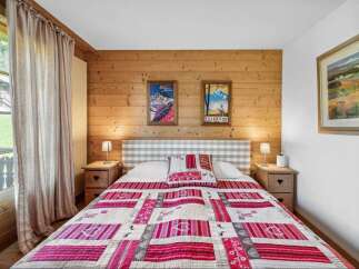 Cozy bedroom with a rustic charm, featuring a wooden wall and a comfortable bed adorned with a vibrant quilt.