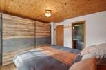 This cozy bedroom features a stunning wooden ceiling and a large, modern wardrobe with a unique design.
