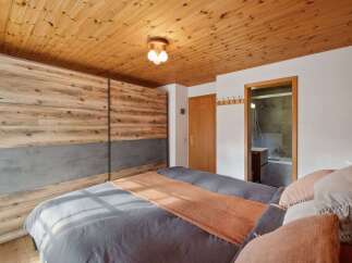 This cozy bedroom features a stunning wooden ceiling and a large, modern wardrobe with a unique design.