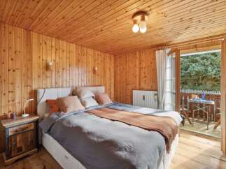 This charming bedroom boasts a warm and inviting ambiance with its wooden walls and ceiling.