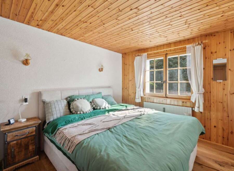 This cozy bedroom features a beautiful wooden ceiling and walls, creating a warm and inviting atmosphere.
