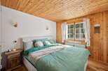 This cozy bedroom features a beautiful wooden ceiling and walls, creating a warm and inviting atmosphere.