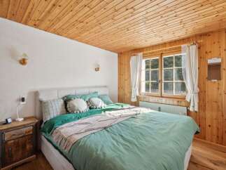 This cozy bedroom features a beautiful wooden ceiling and walls, creating a warm and inviting atmosphere.