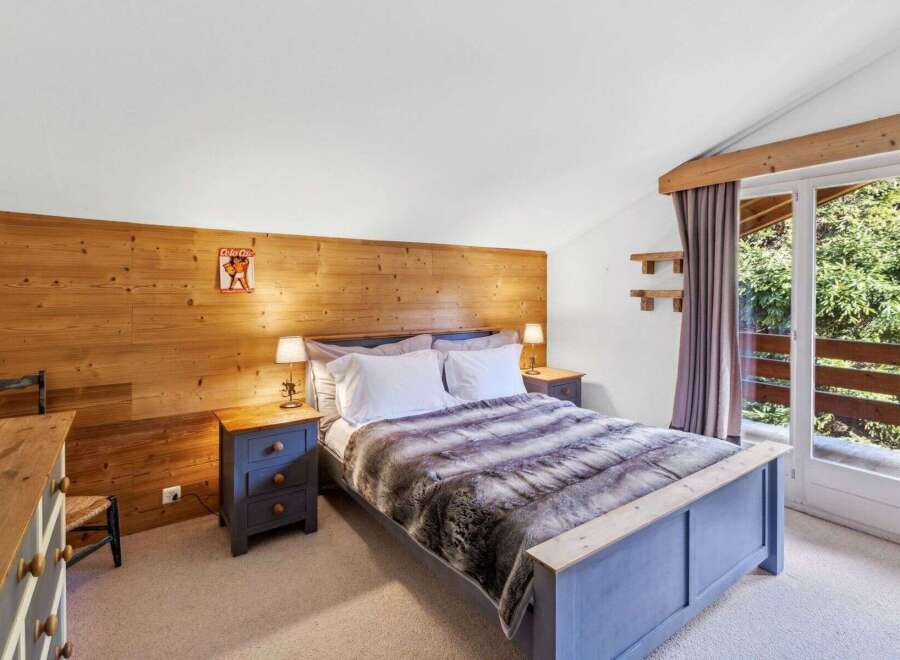 This cozy bedroom features a rustic wooden accent wall and a comfortable bed with a faux fur throw.