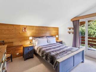 This cozy bedroom features a rustic wooden accent wall and a comfortable bed with a faux fur throw.